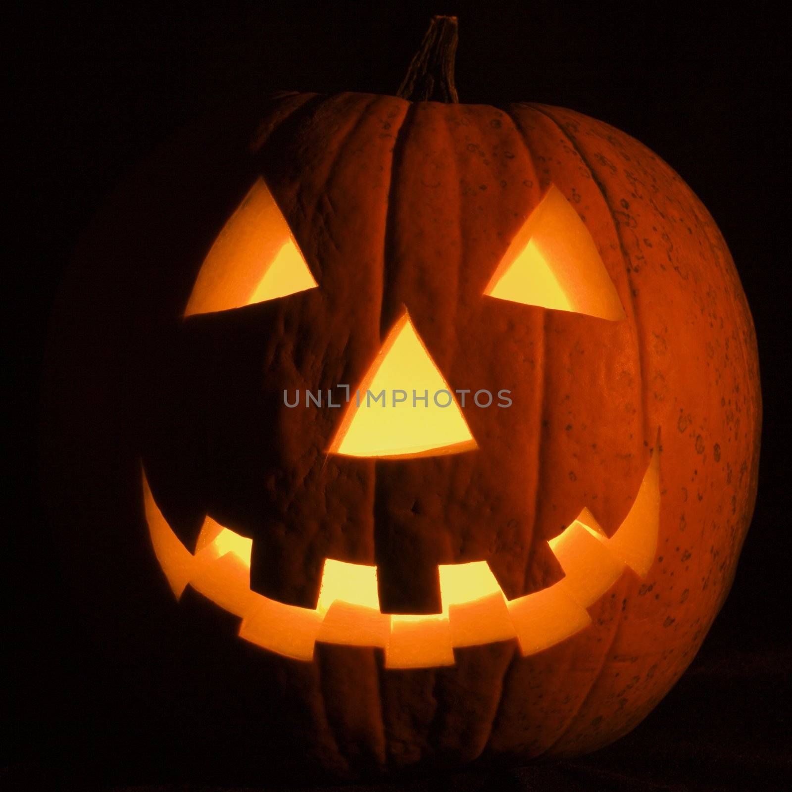 Carved Halloween pumpkin glowing in the dark.