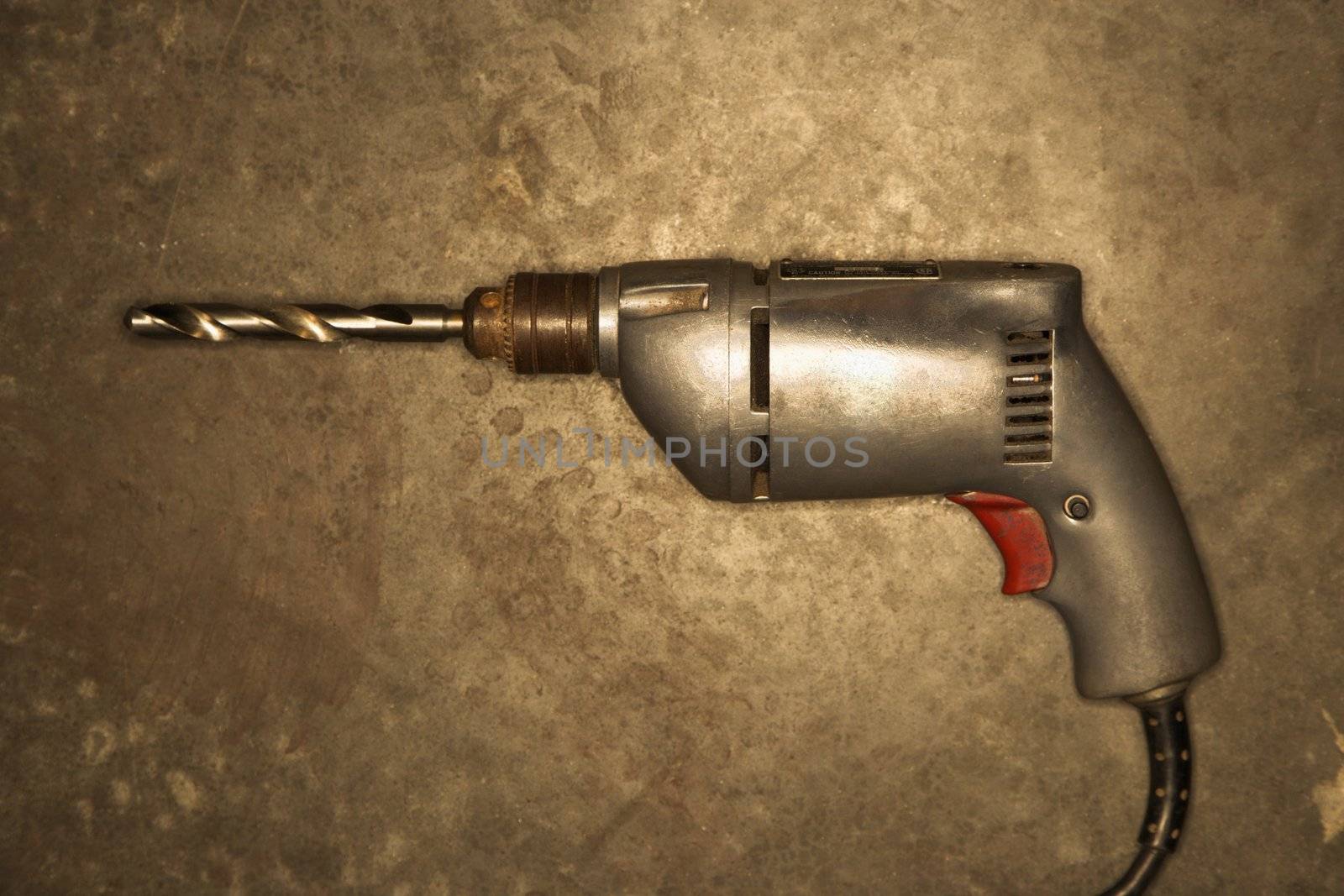 Electric drill resting on cement floor.