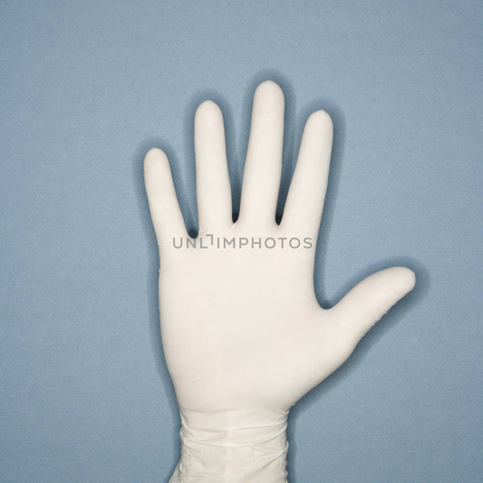 Hand with five fingers extended wearing white rubber glove.