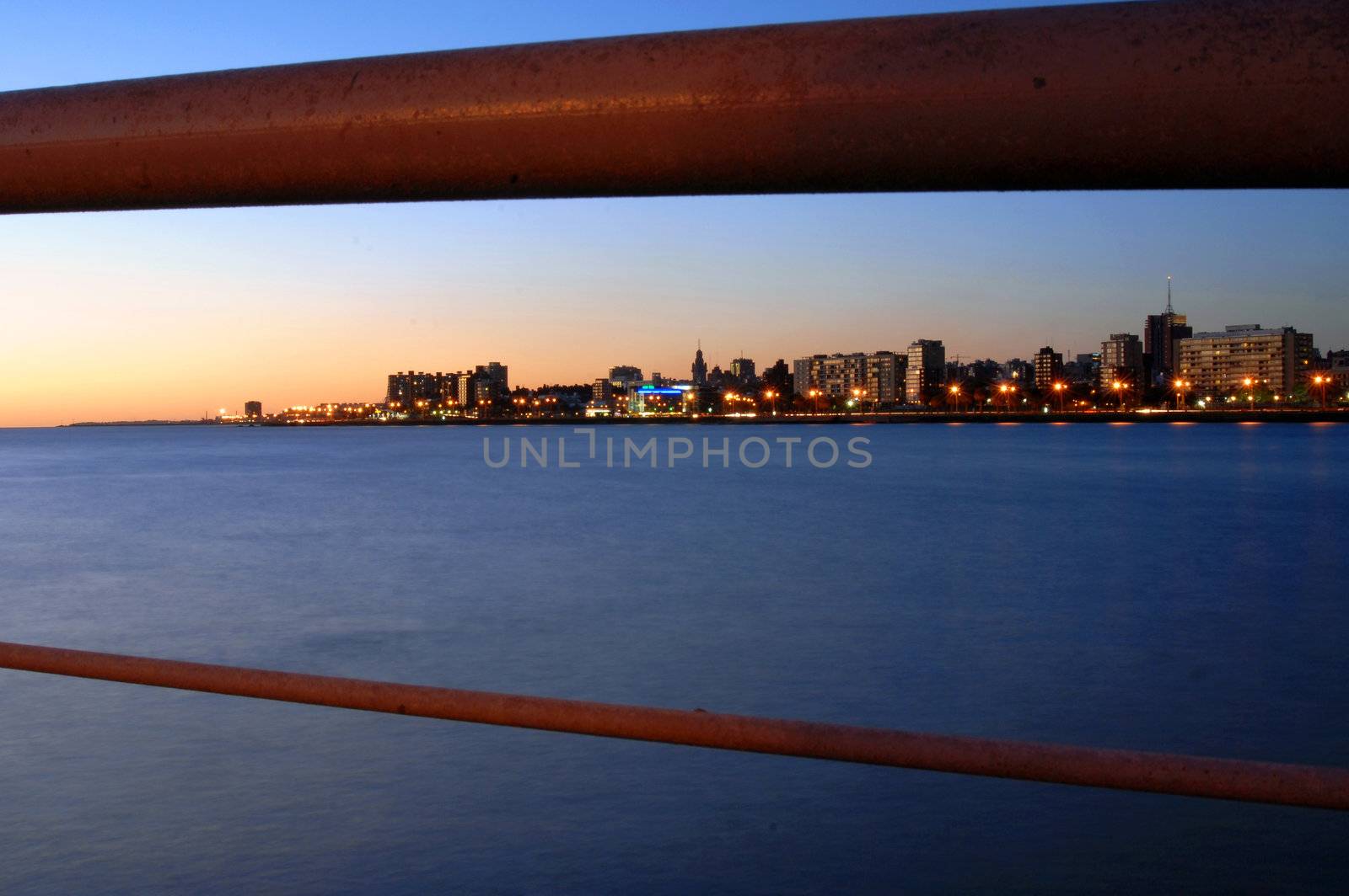 Coastline landscape of modern buildings at sunset behind bridge railing