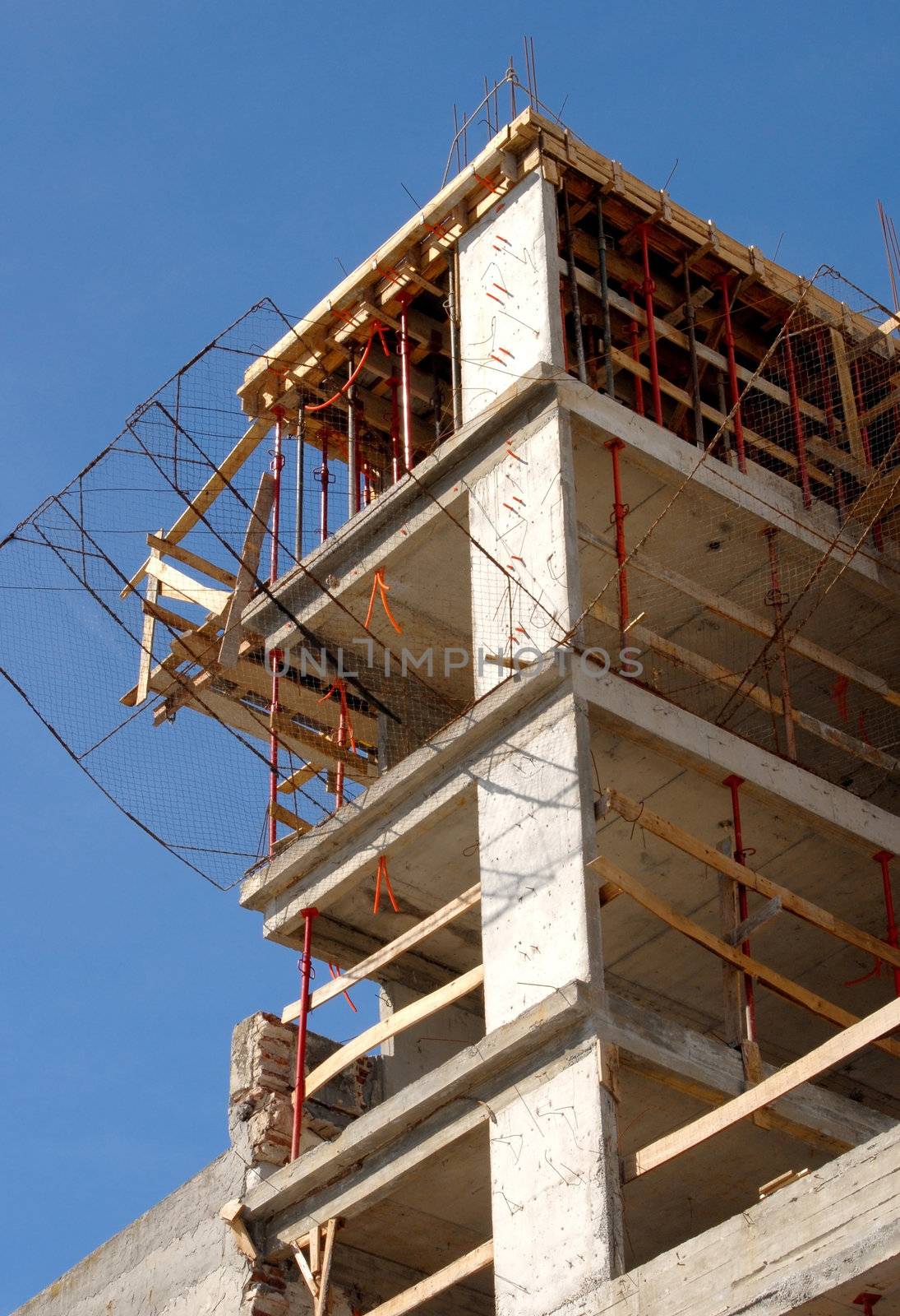 Detail of the upper part of a building under construction on a blue sky background