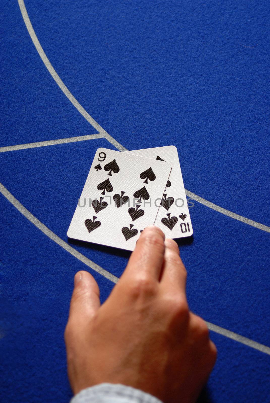 Two poker or baccarat cards on a Casino table. Male hand holding them