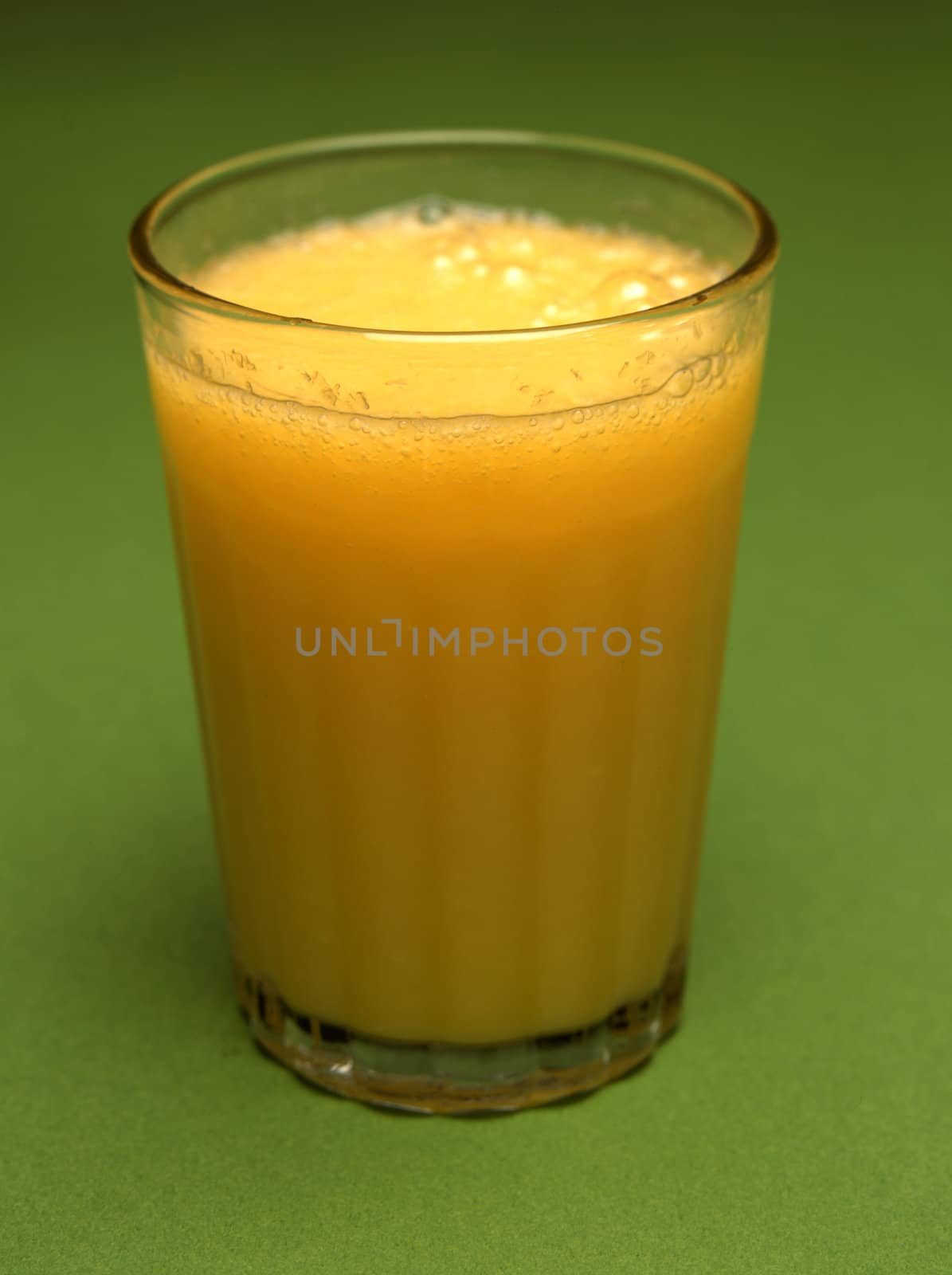 A glass of orange juice on green background
