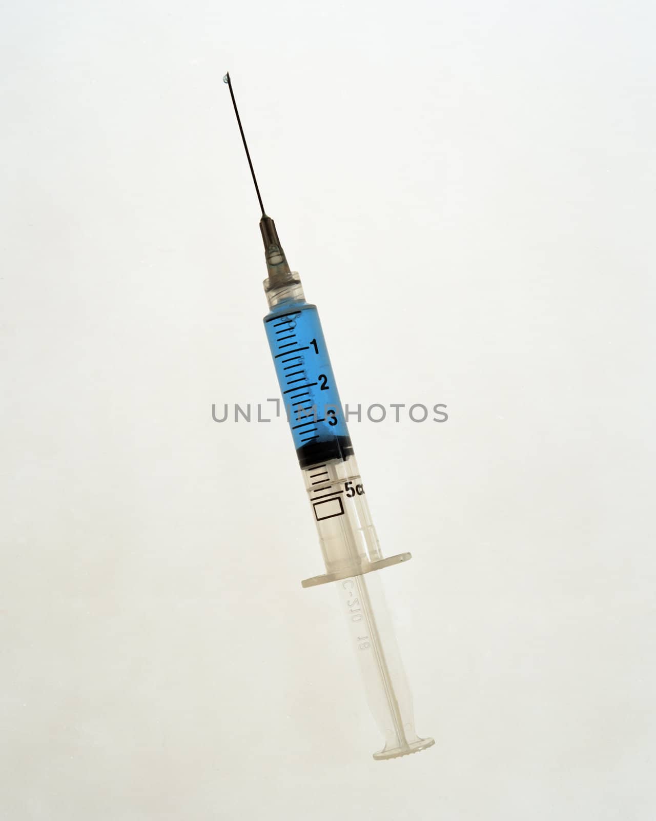 Syringe with blue liquid on white
