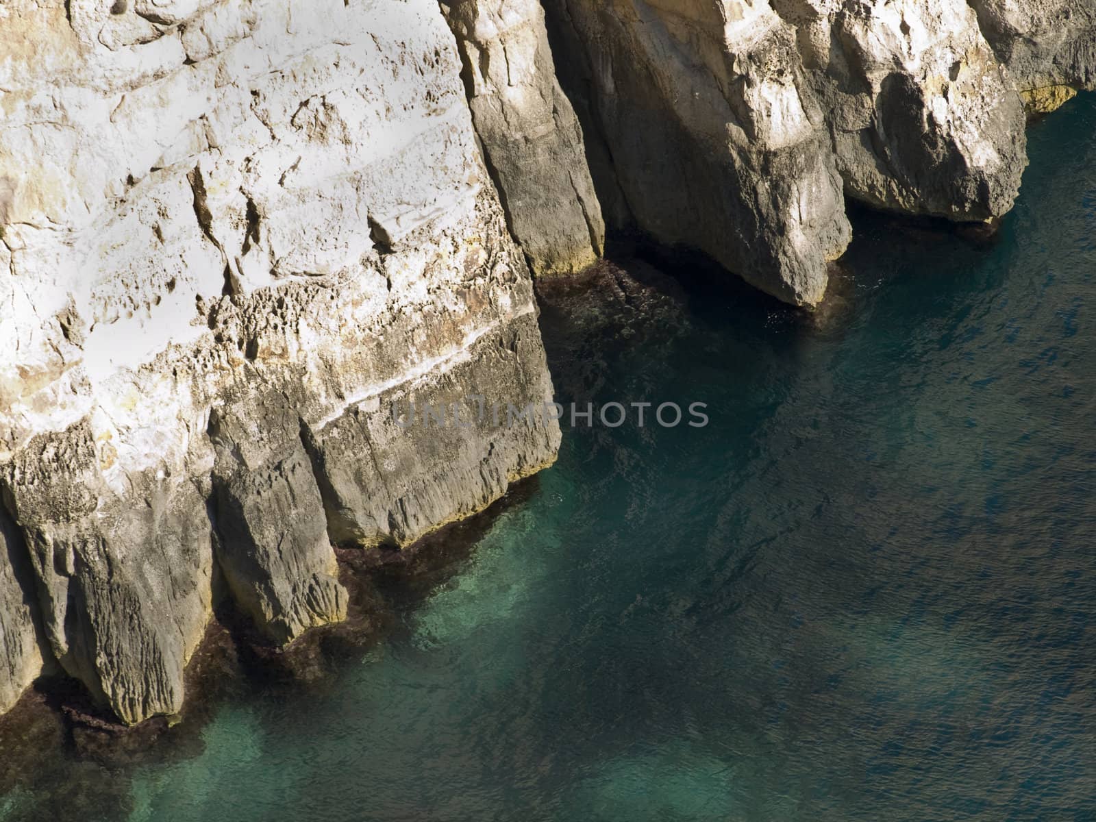 Deep clear emerald sea next to coastal cliff