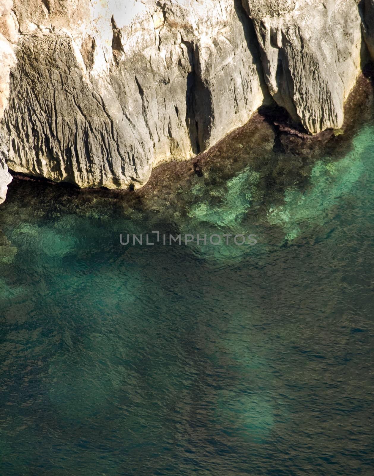 Deep clear emerald sea next to coastal cliff