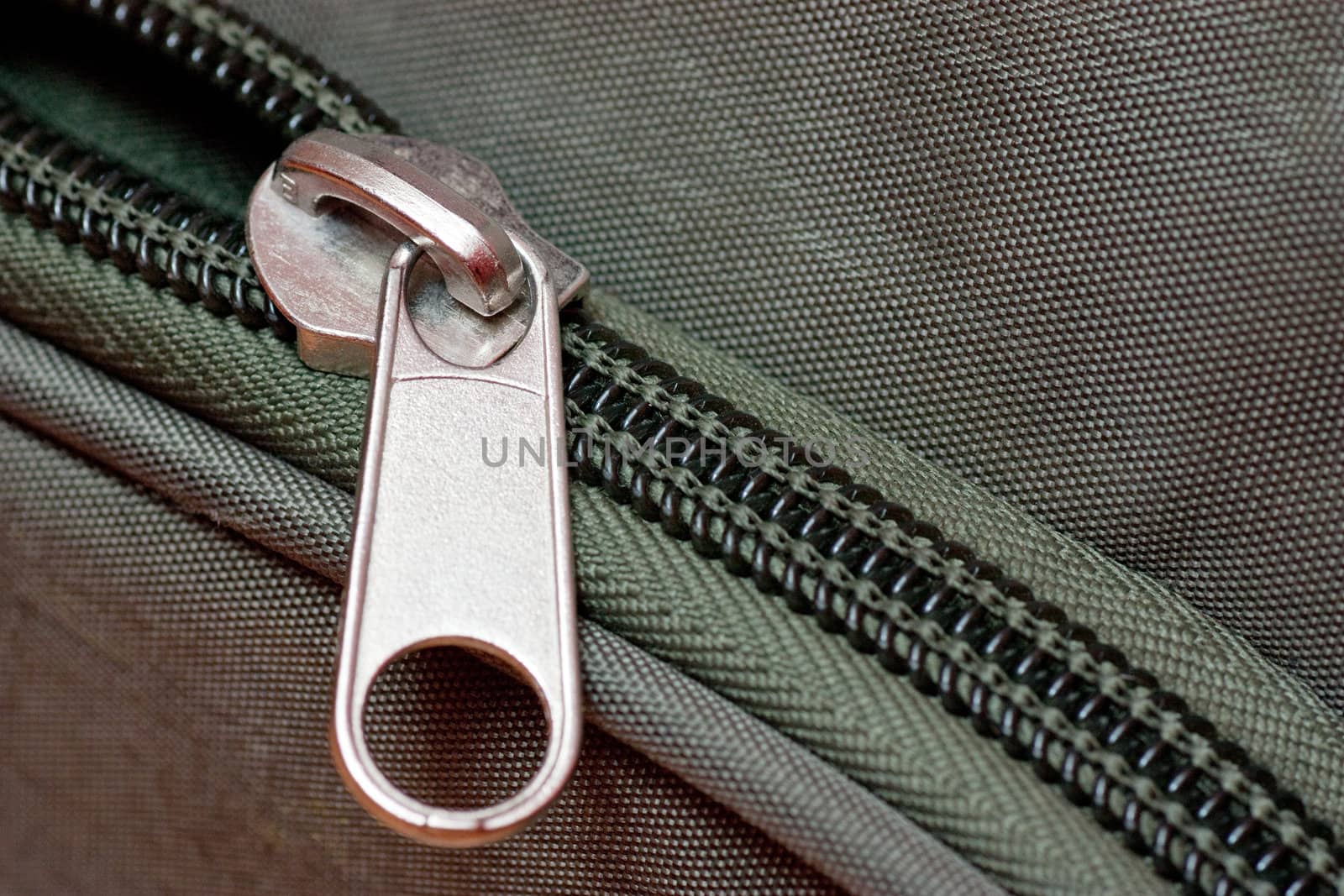 Close-up of a half-opened zipper on a green bag.