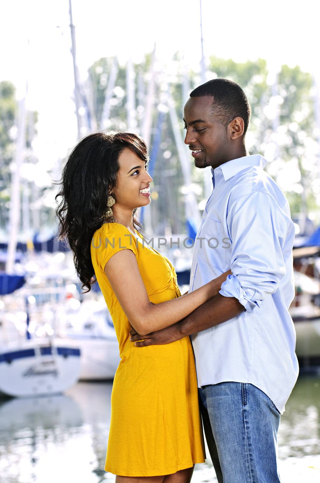 Young romantic couple facing each other hugging and standing at harbor