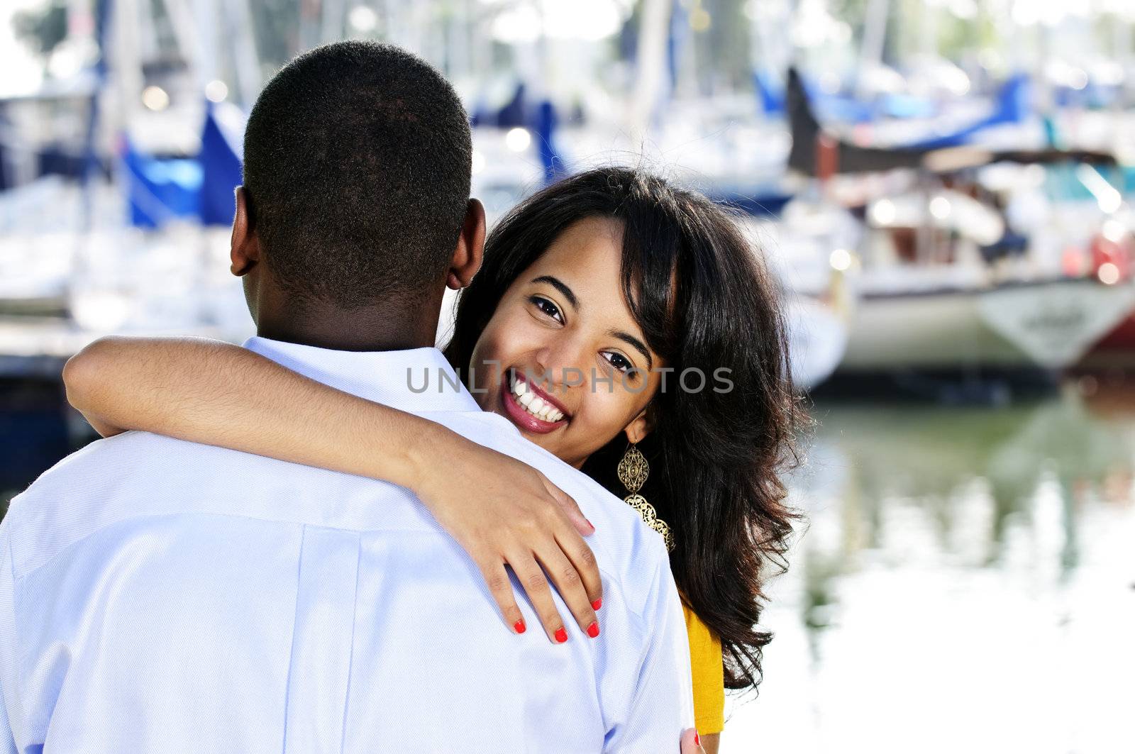 Beautiful young woman hugging boyfriend standing at harbor