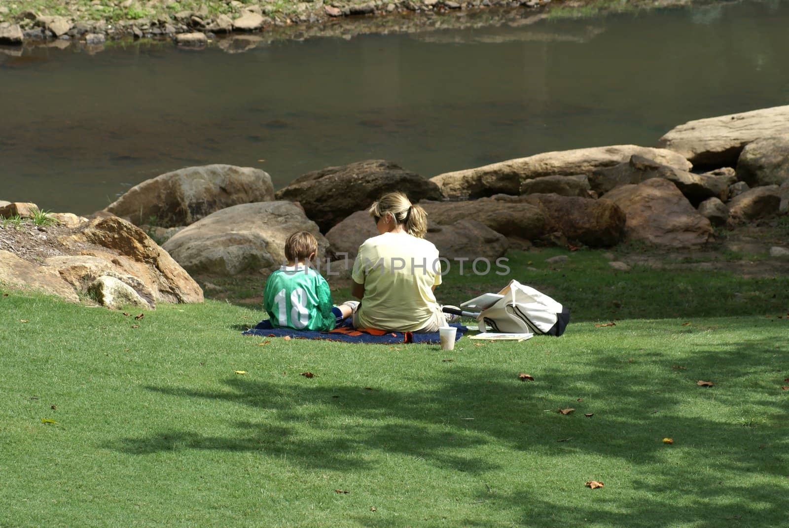 Young boy and his mother on a picnic by the river.               