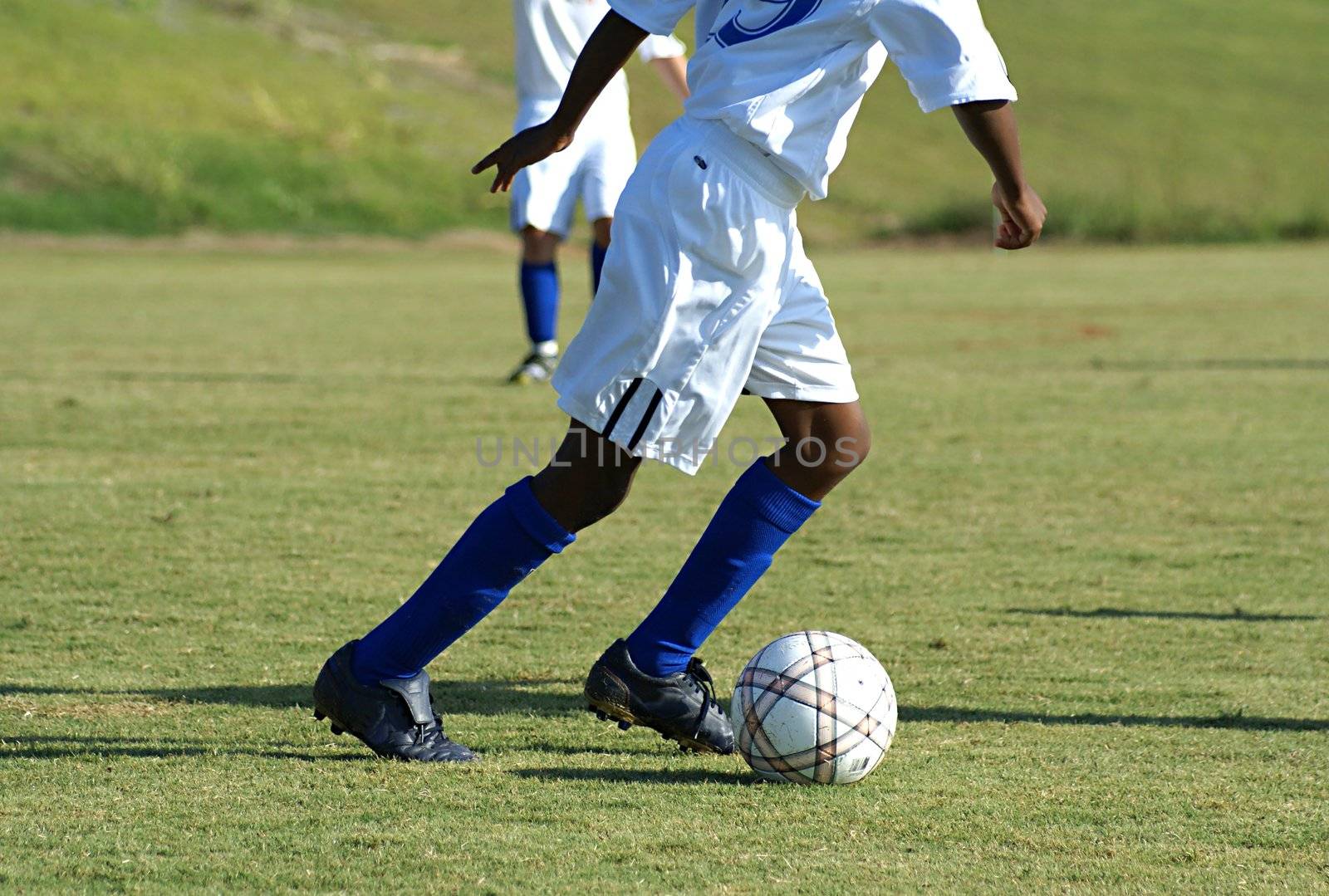 Young boy running with ball in a soccer game.               