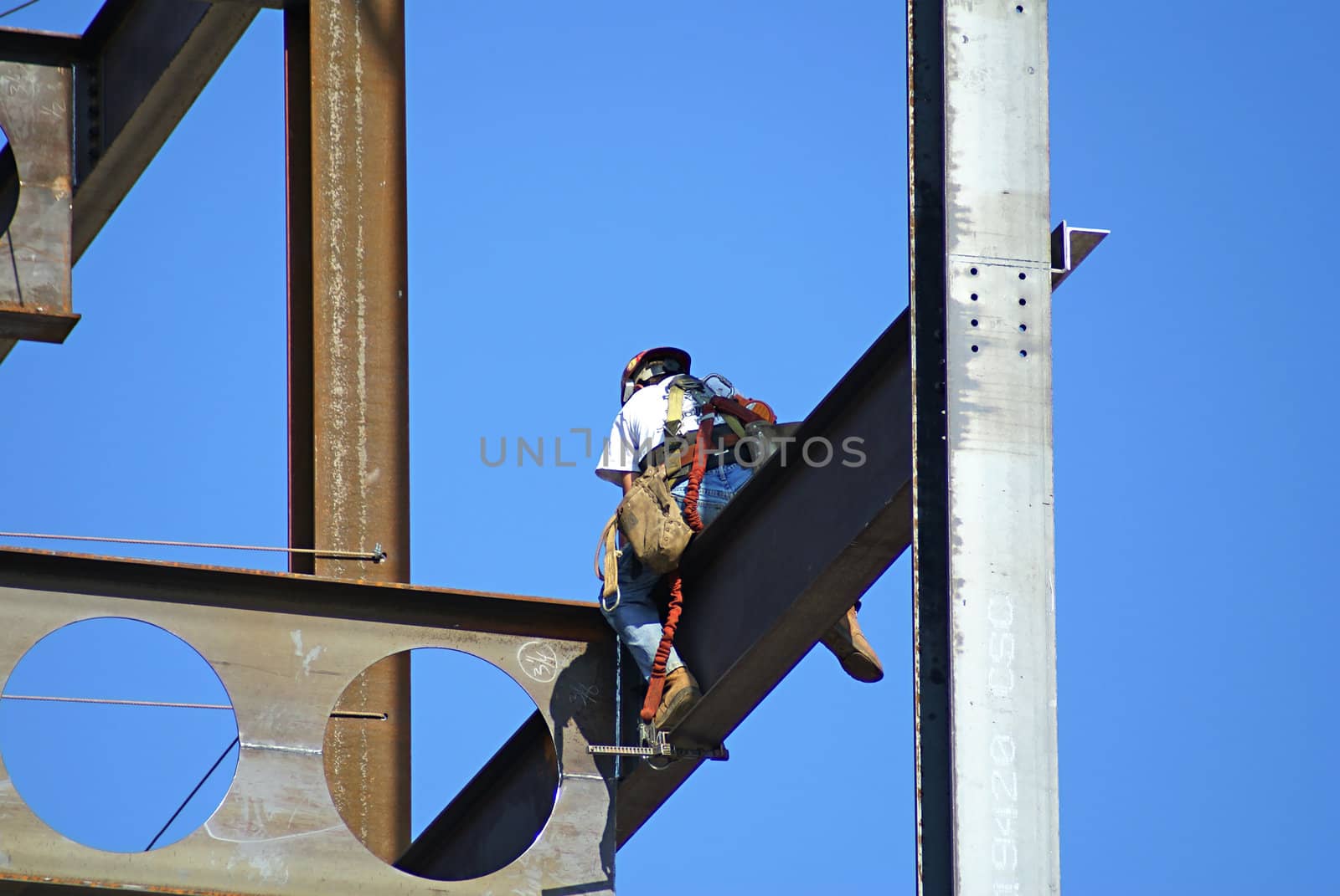 Man working on a skyscraper holding on to beam.                  