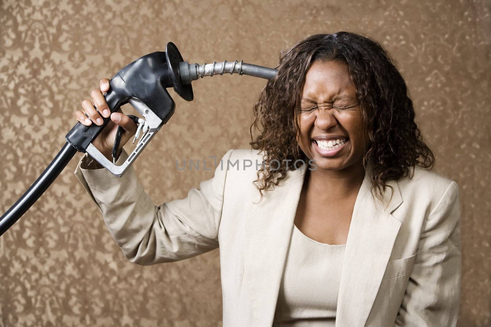 Woman holding gas nozzle like a gun to her head