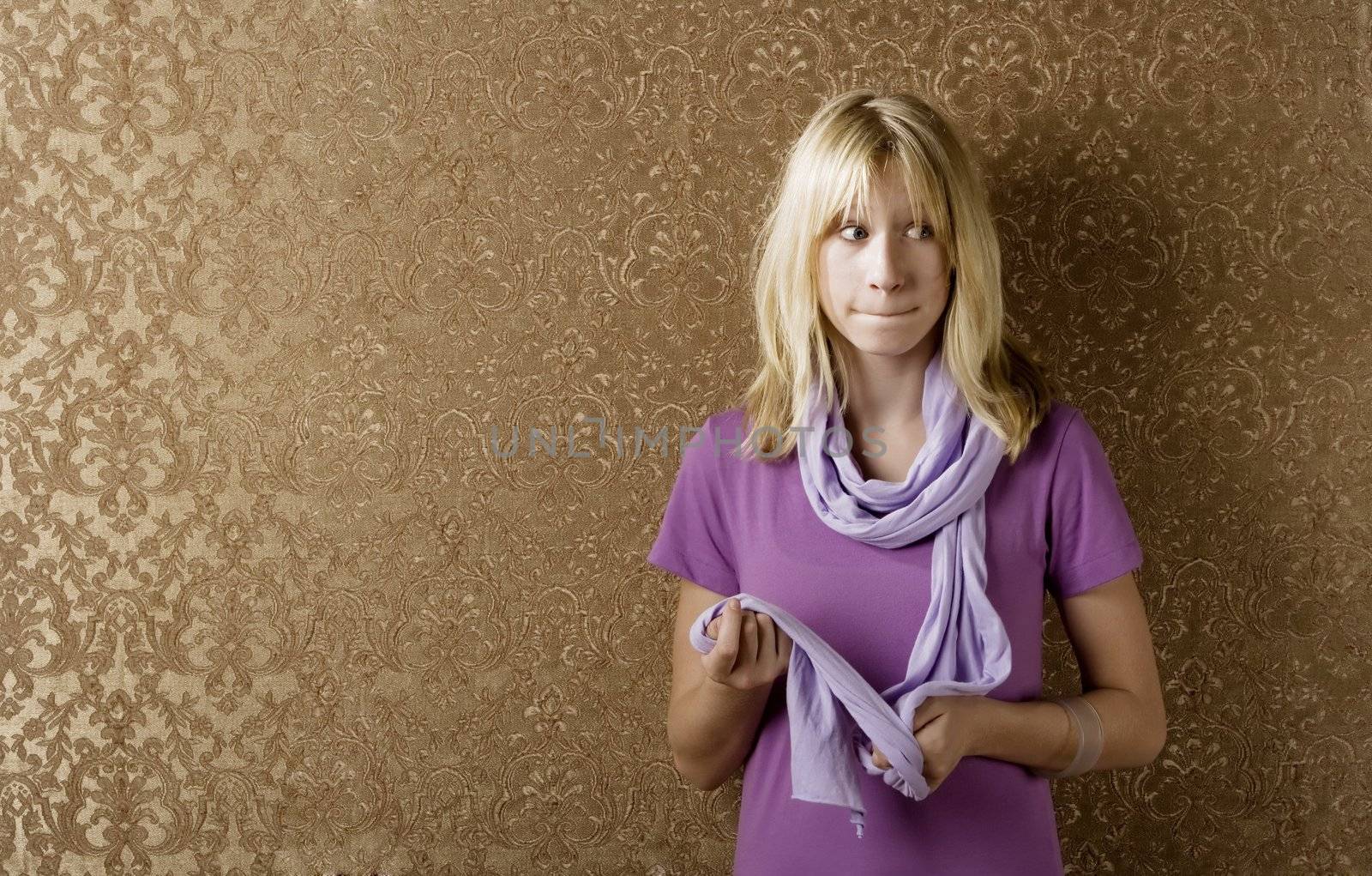 Apprehensive young girl leaning against a wall with gold wallpaper