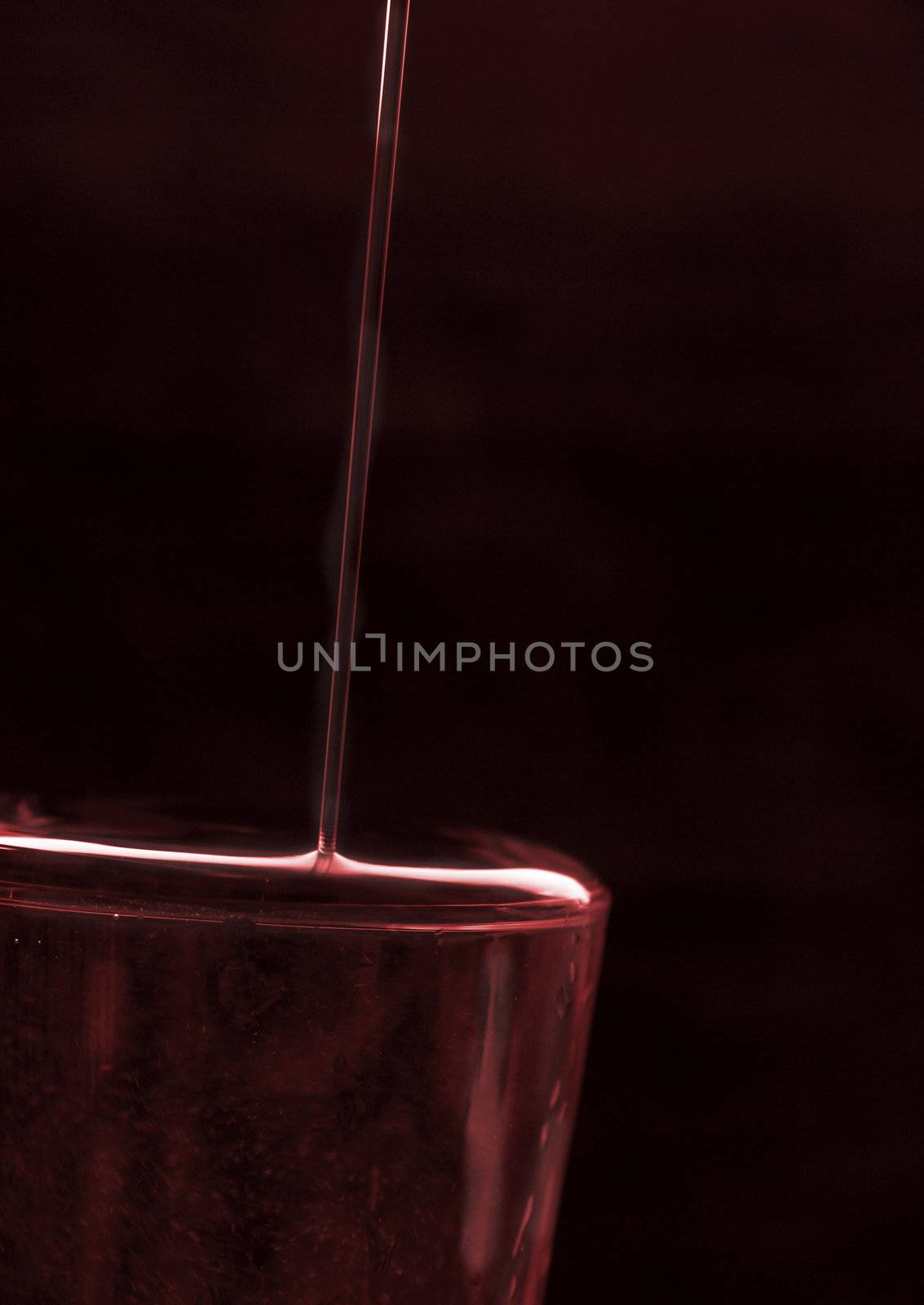 overflowing glass of red red wine against a dark background