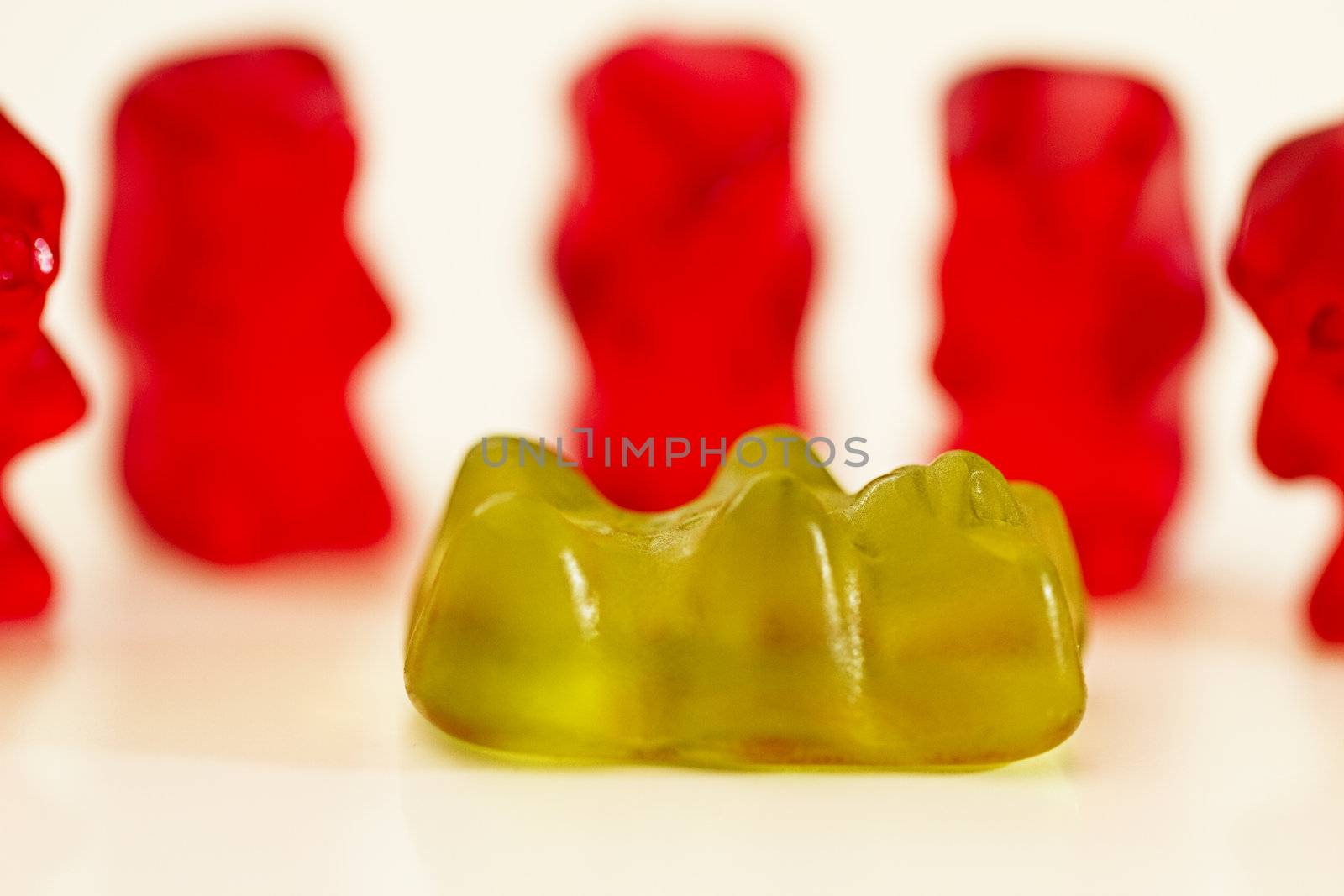 one green gummibear lies in front of red gummibears