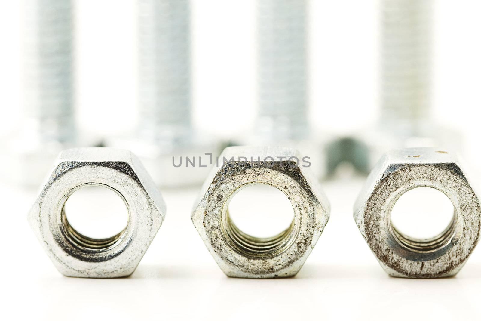 three silver bolts in front of screws on white background