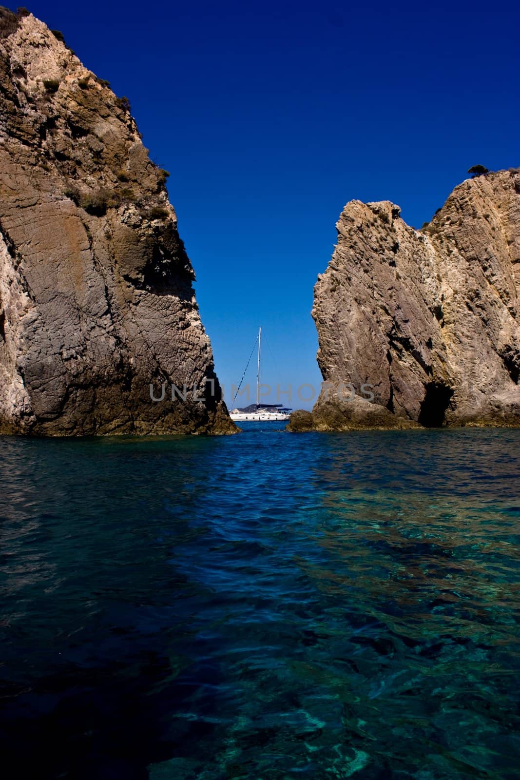 Yacht cruising between two rocks in Ponza island, Italy