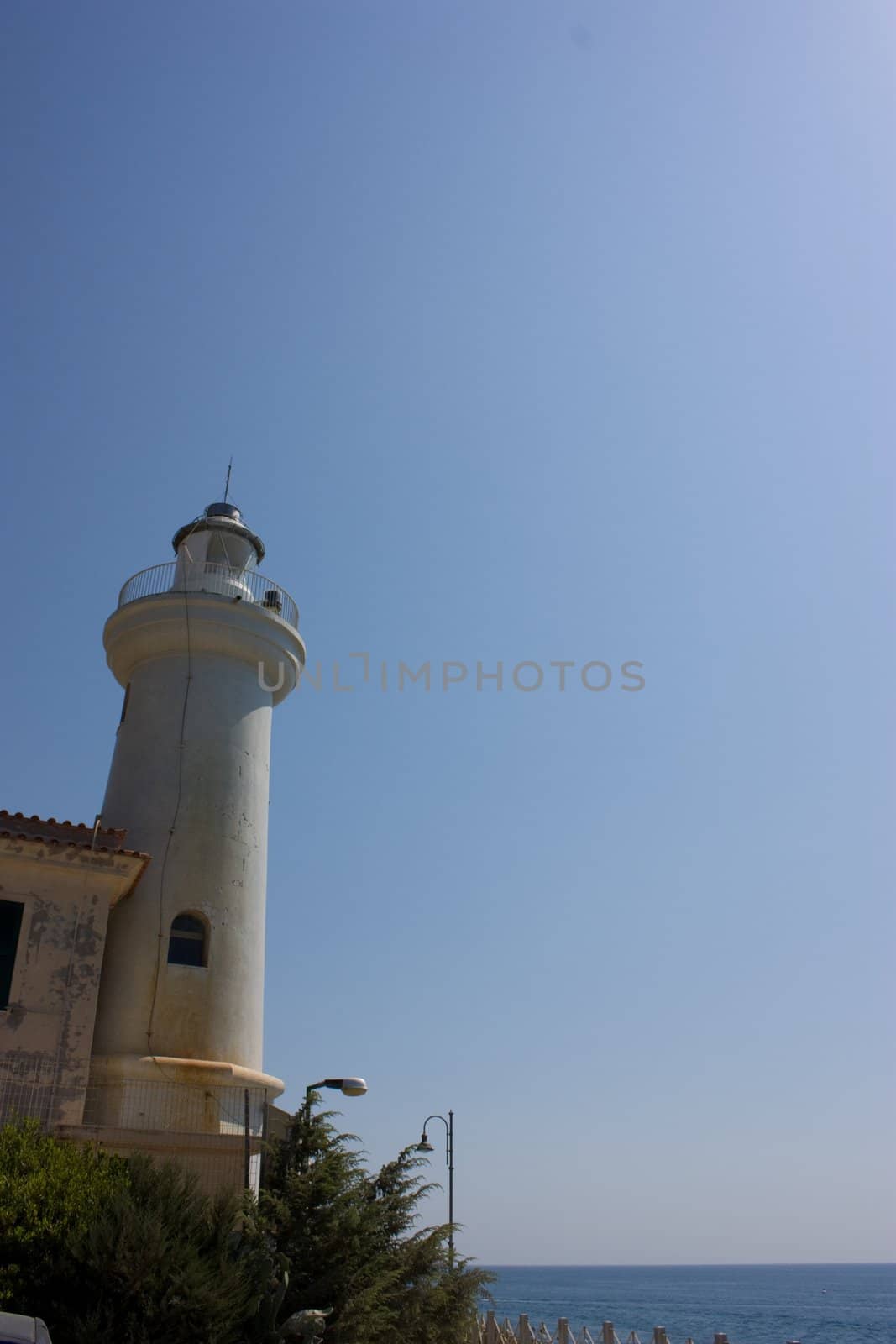 White lighthouse on blue sky background in Italy