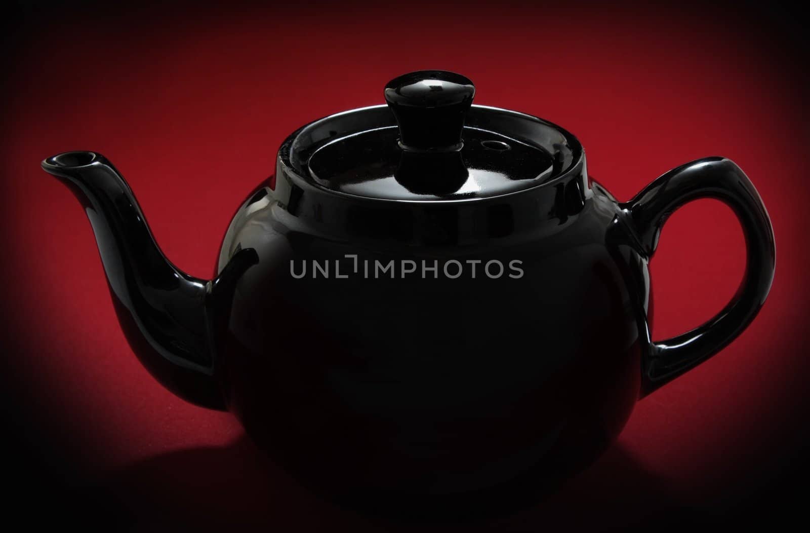 red teapot over red background