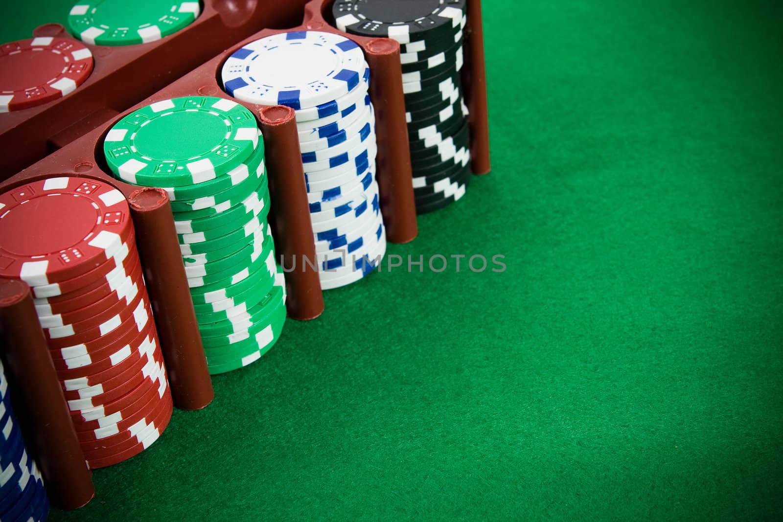 Poker chips in a box on green poker table.