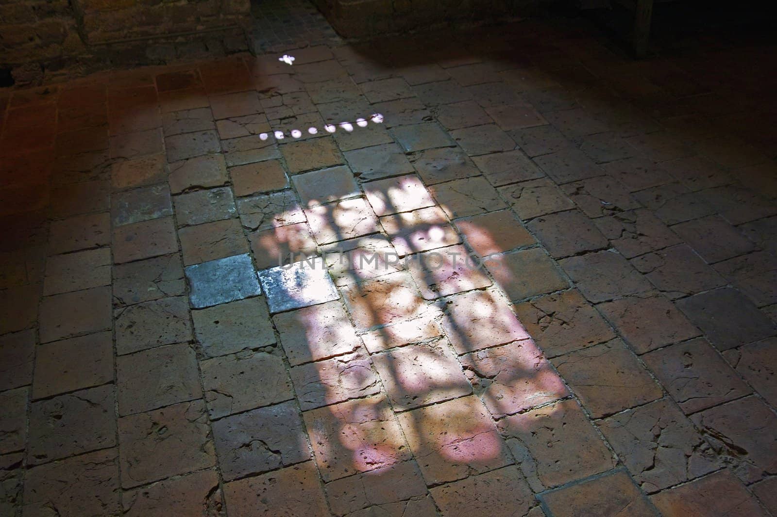 Through a window of the Ruins of Brederode colored light plays with the colored tiles