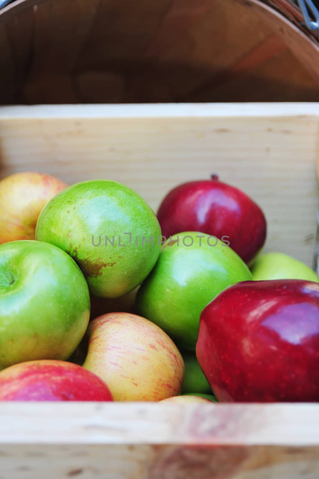 A wooden crate contains three different kinds of apples, Pippin, Red Delicious and Fuji.