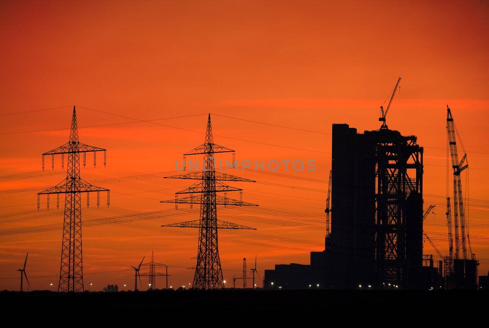 Power plant, power lines and wind turbines at sunset