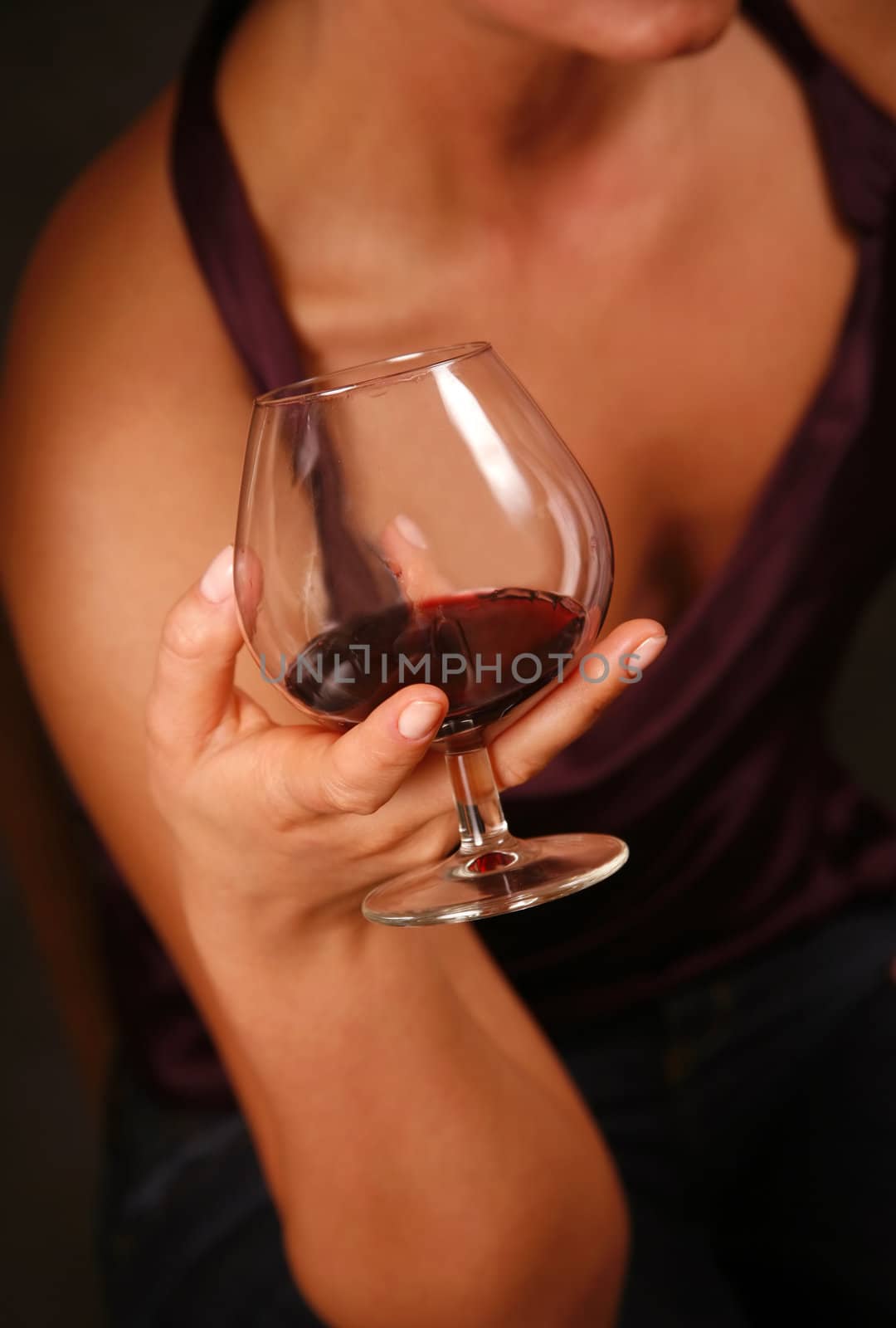 The image of a glass with a red wine in a female hand