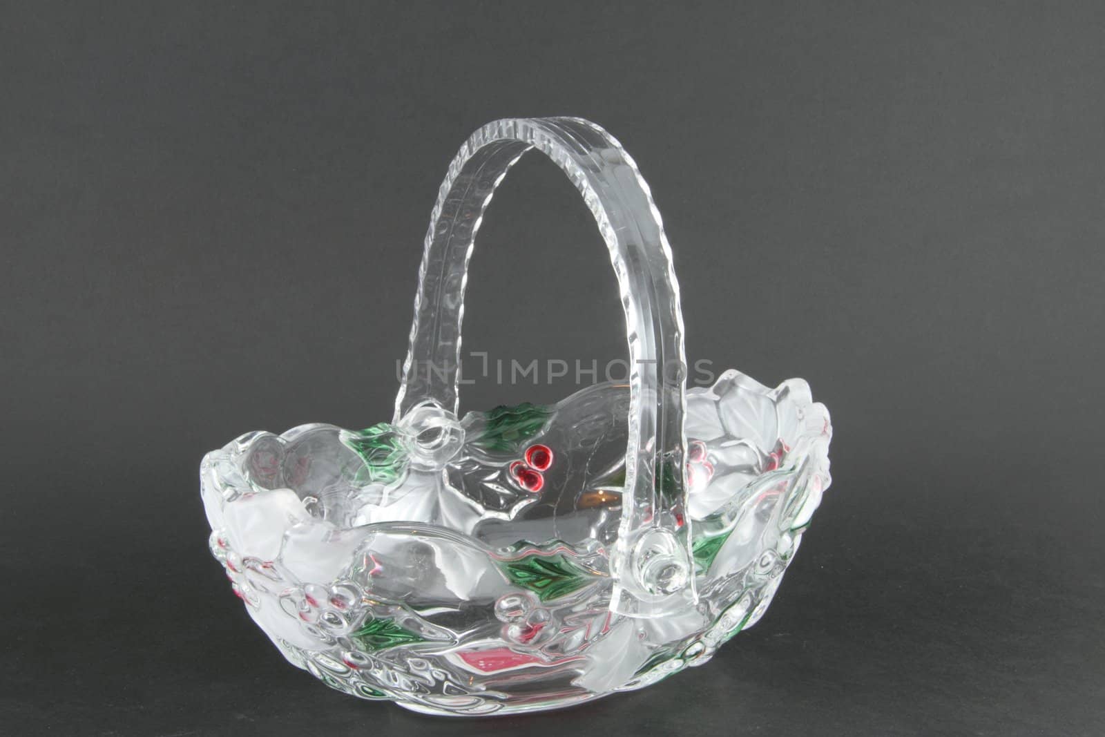 A glass basket with a Christmas theme on a grey background.