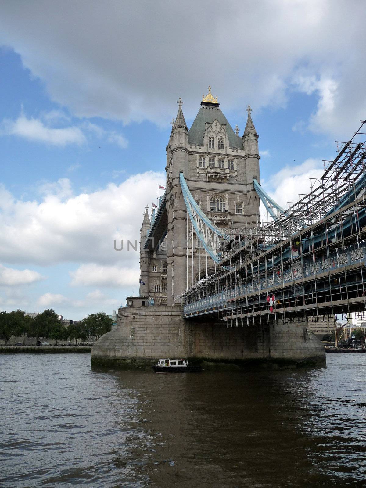 A view of the historic Tower Bridge partly covered in scaffolding, which is located over the River Thames in London.
.