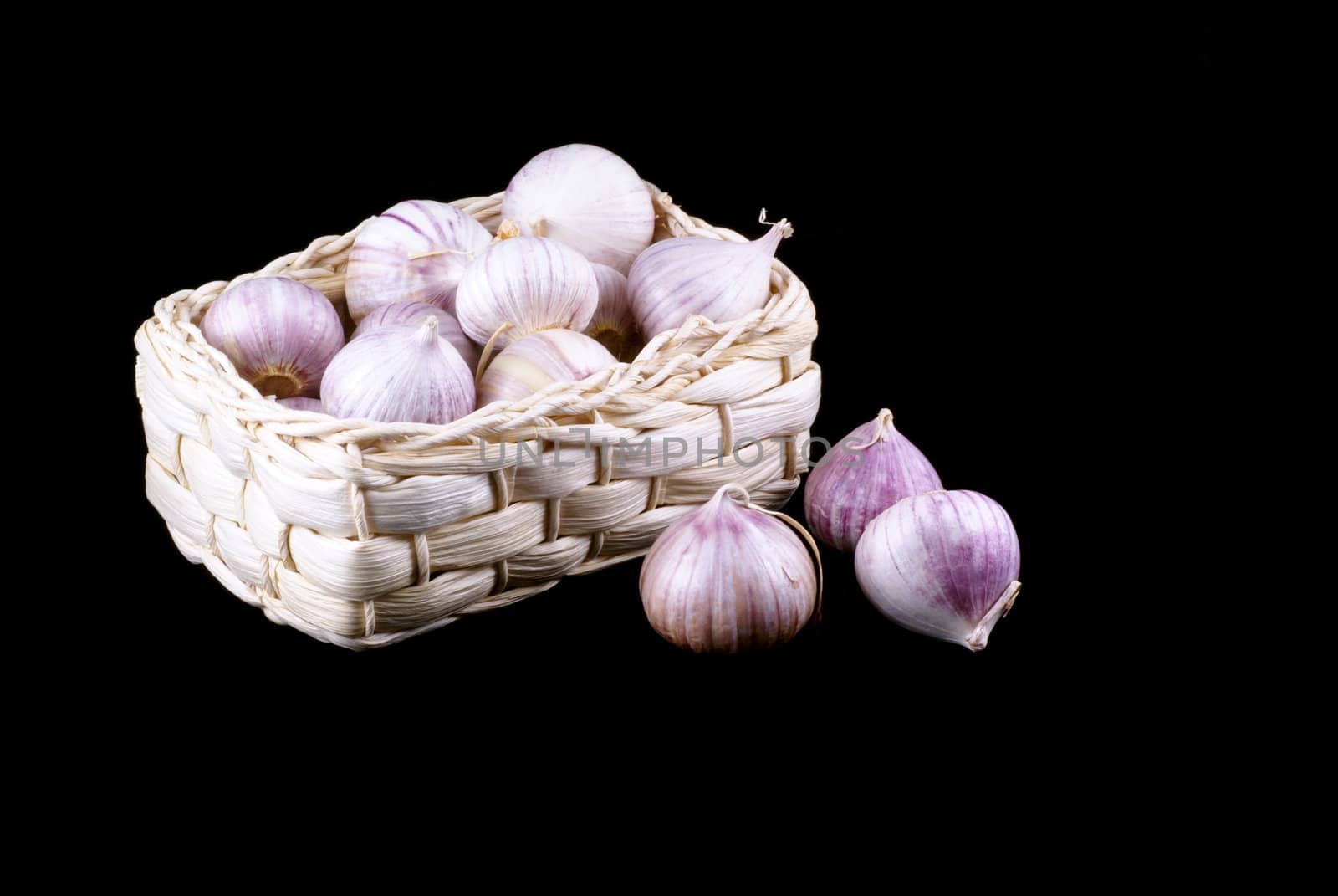 Basket full of garlic isolated on a black background.