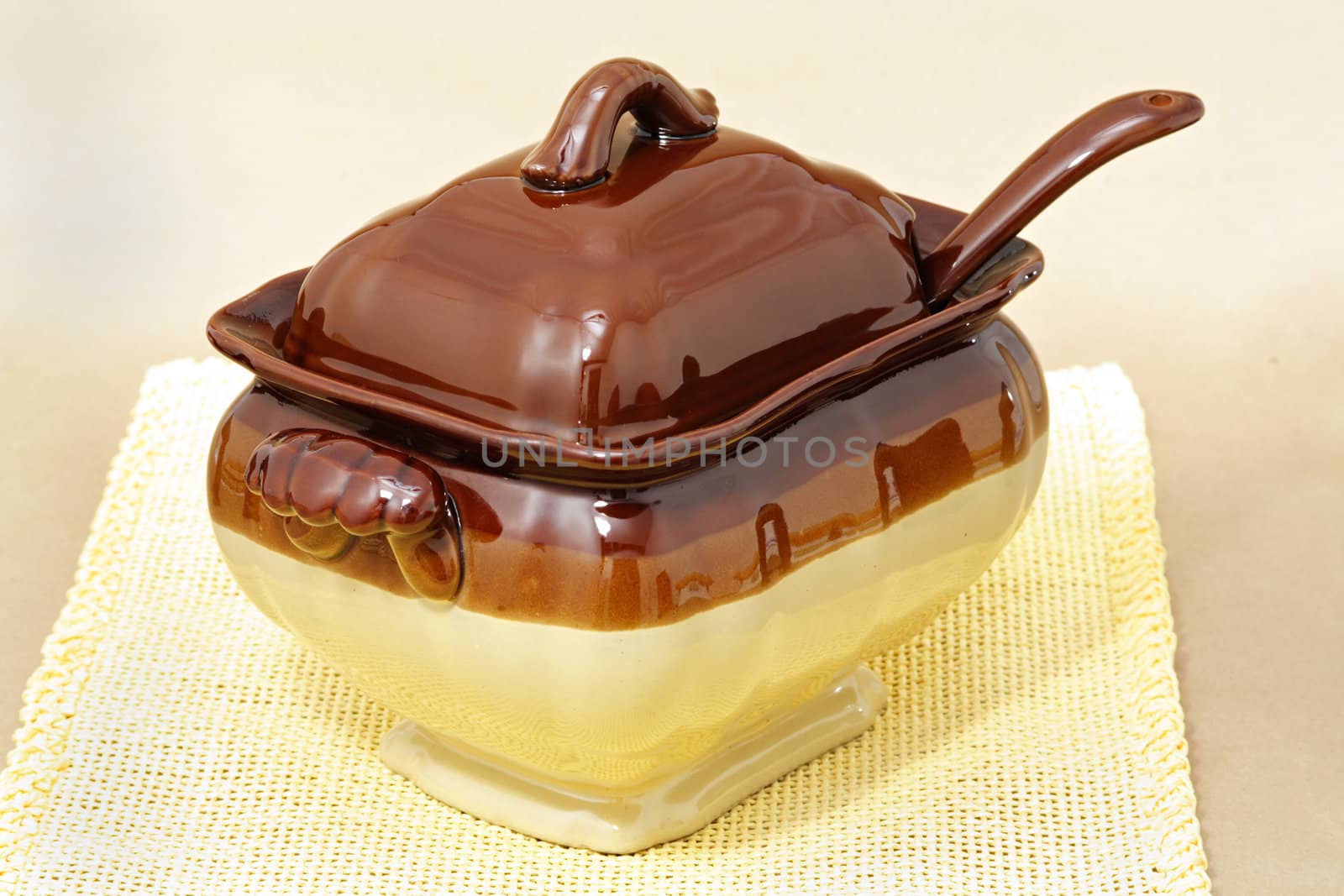 soup tureen on yellow tablecloth, beige background