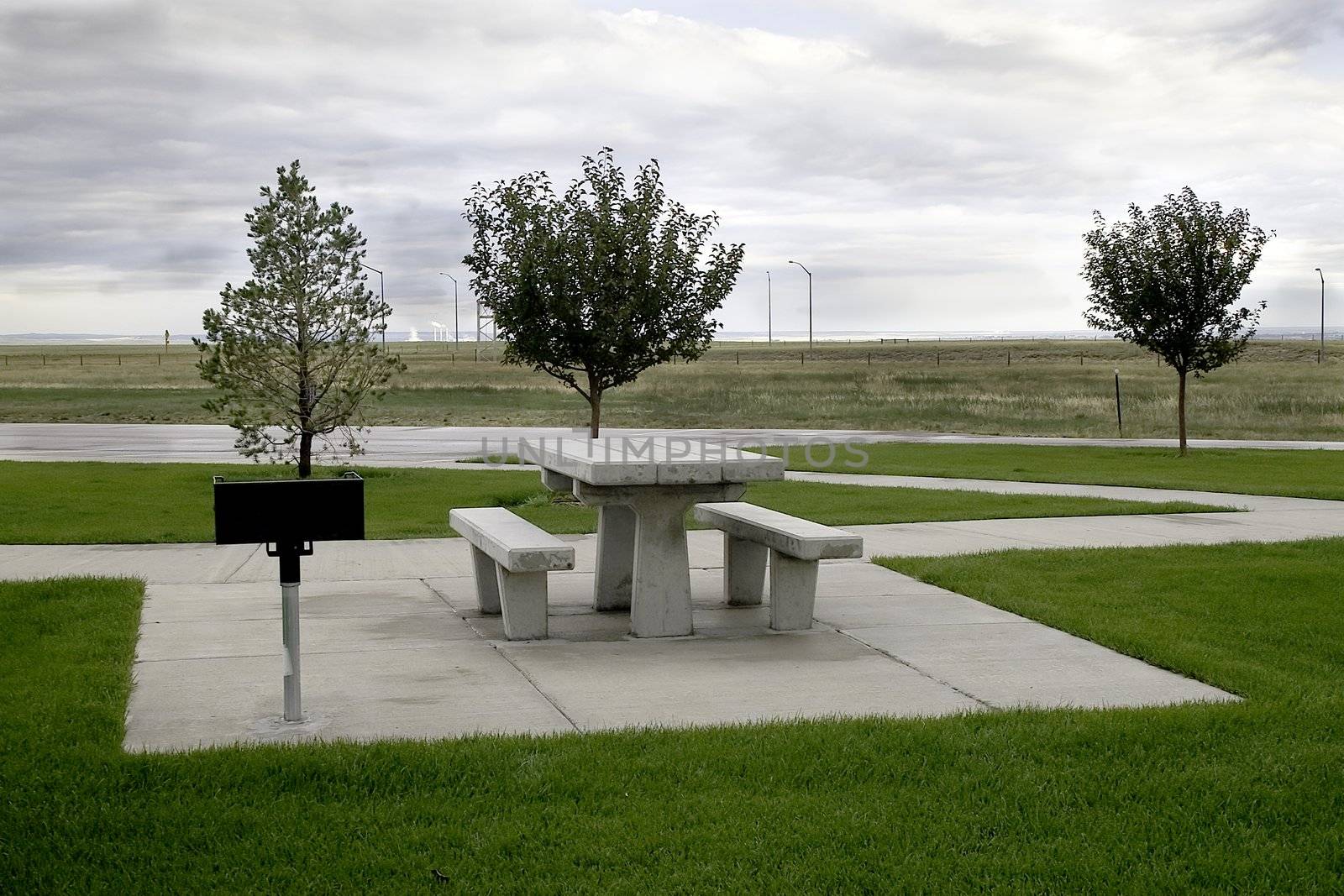 A modern concrete picnic spot at a Wyoming interstate rest area with a power plant in the background.