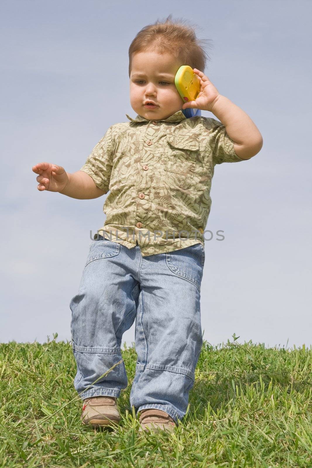 Little boy holding a toy cellphone near his ear