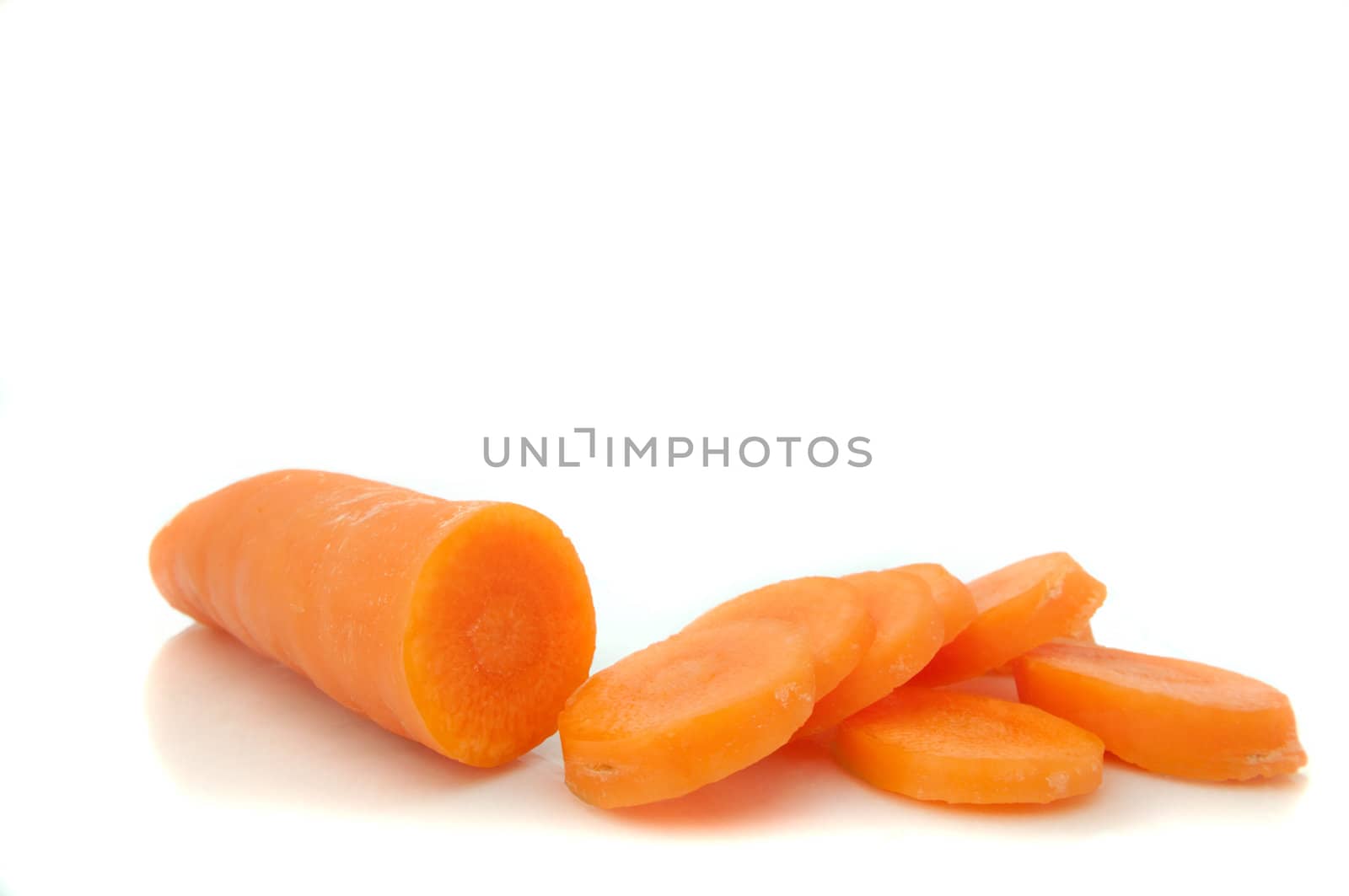 Close and low level capturing a partially sliced fresh carrot arranged over white.
