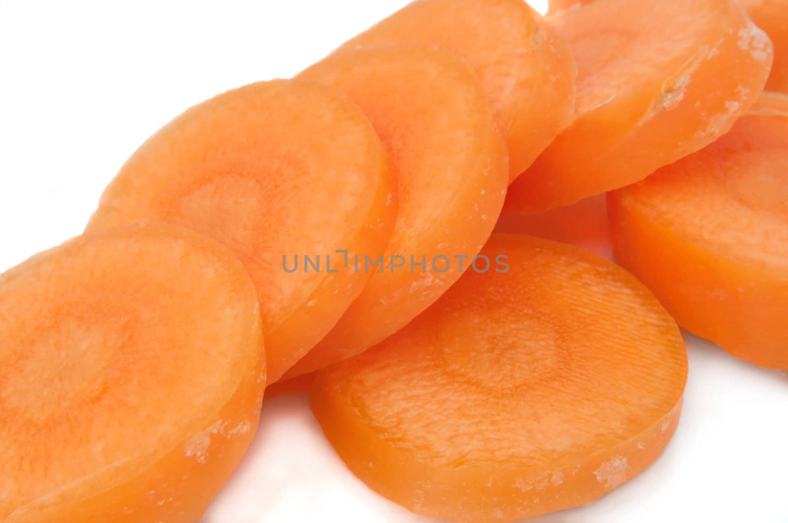 Close and low level angle capturing fresh carrot slices arranged over white.