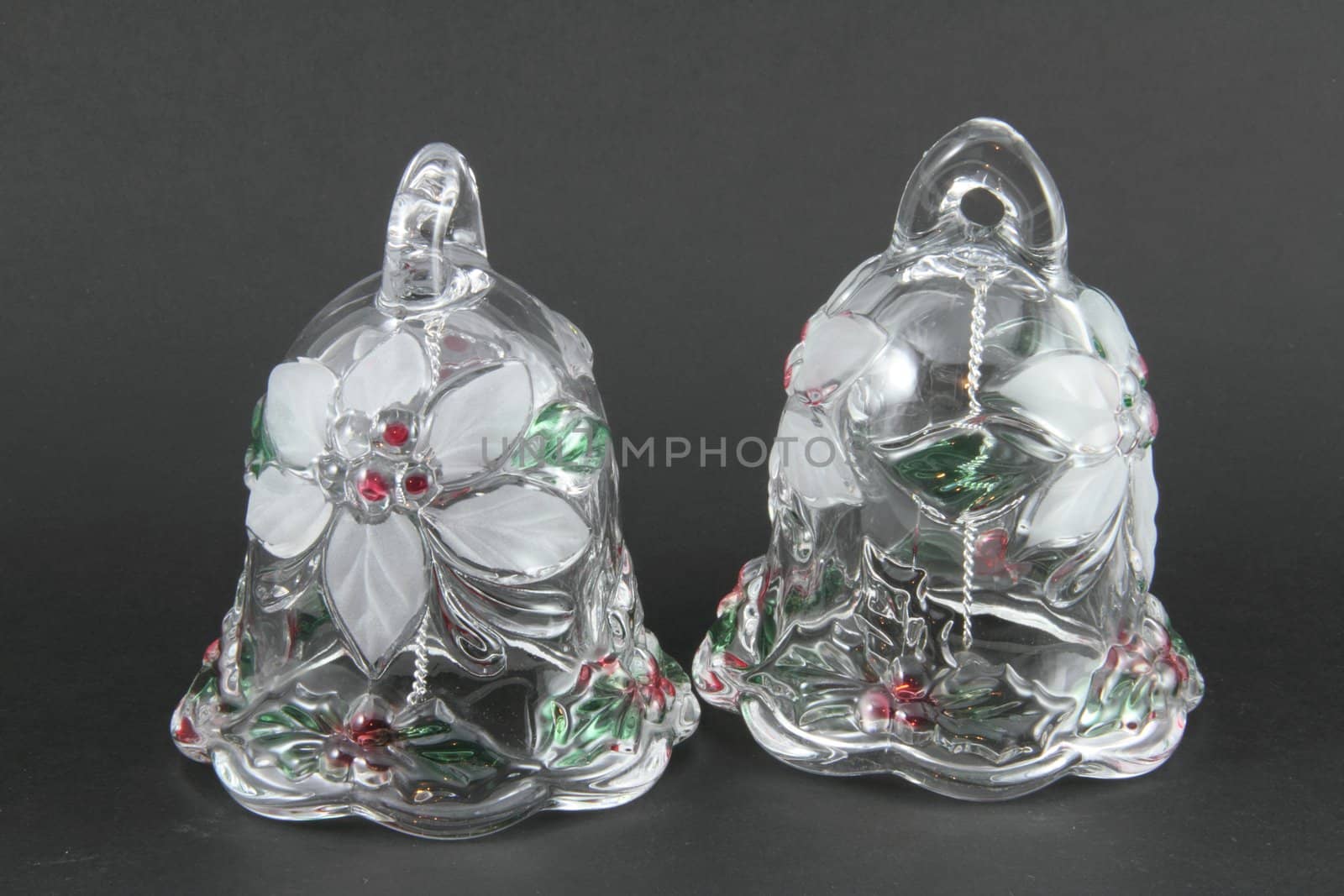 A pair of glass Christmas bells on a grey background.