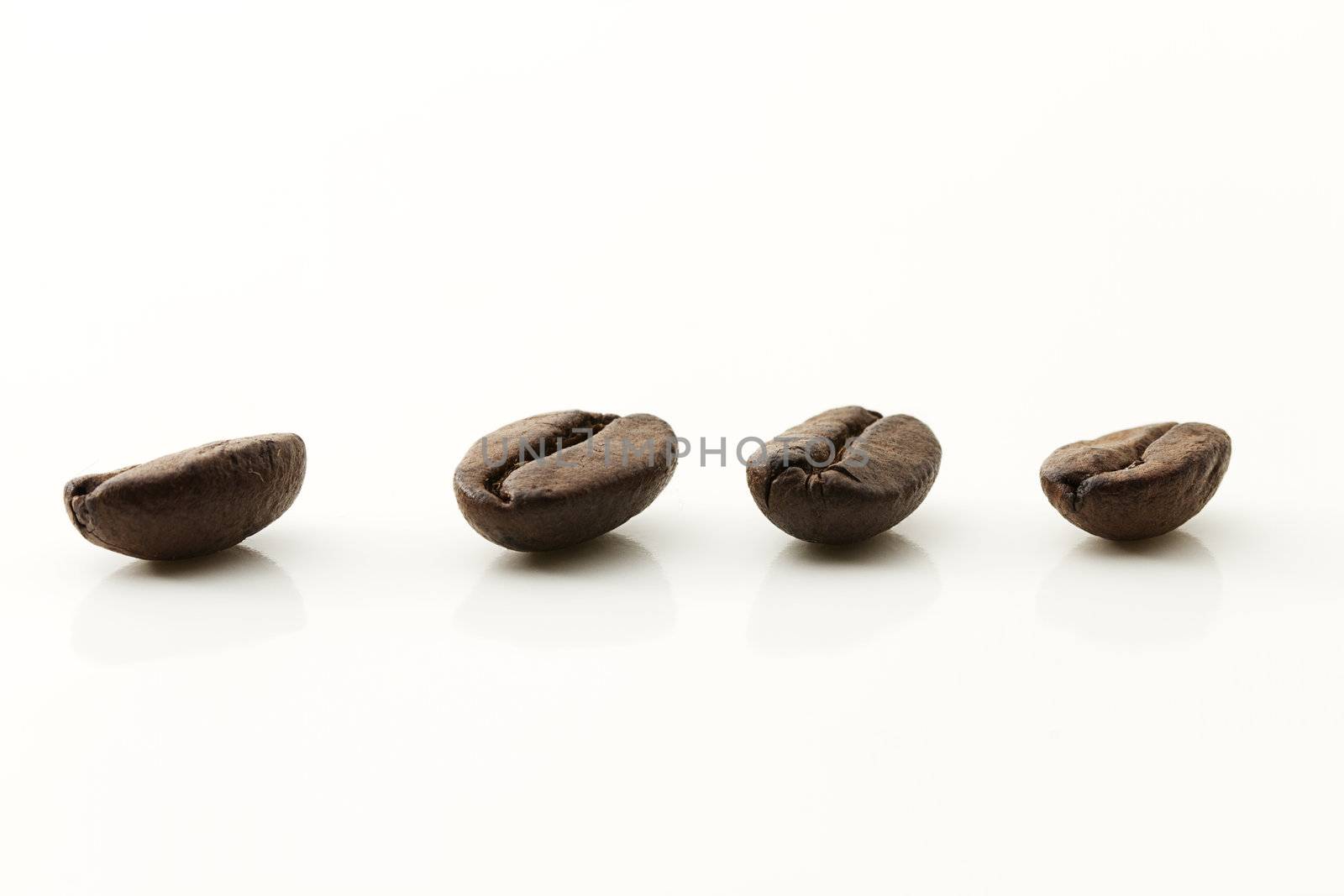closeup of four coffee beans on white background