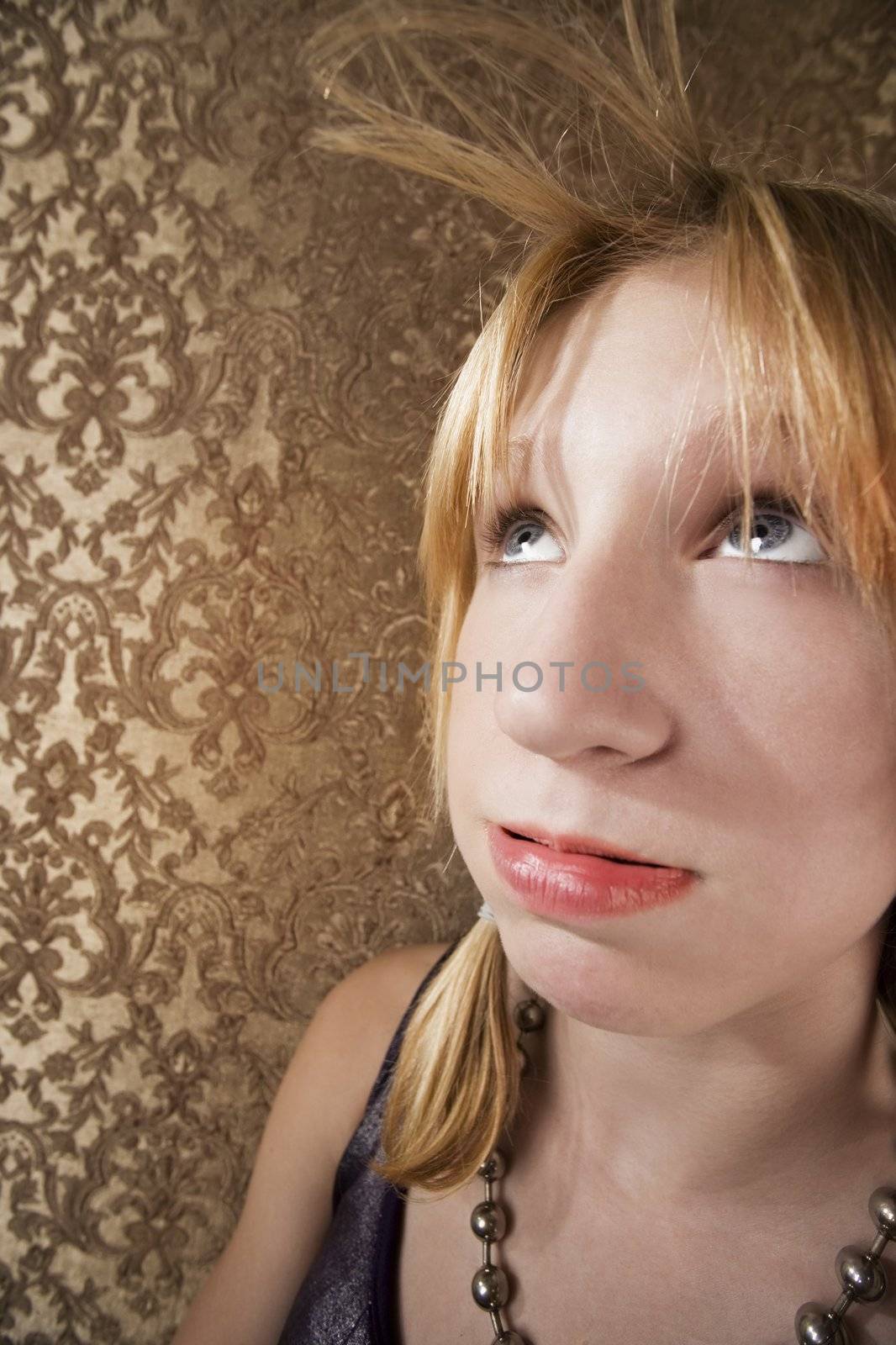 Bored blonde teenager blowing her hair bangs