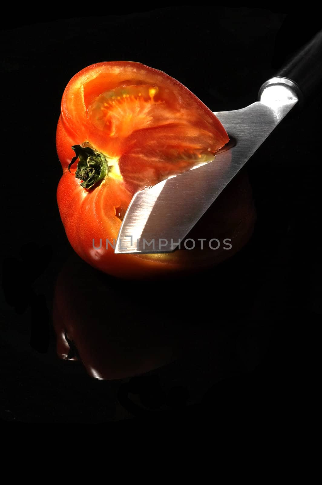 tomato sliced with knife on black background