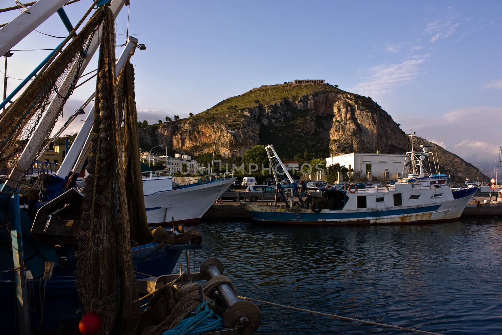 Italian harbor with fishing boats and old temple on background
