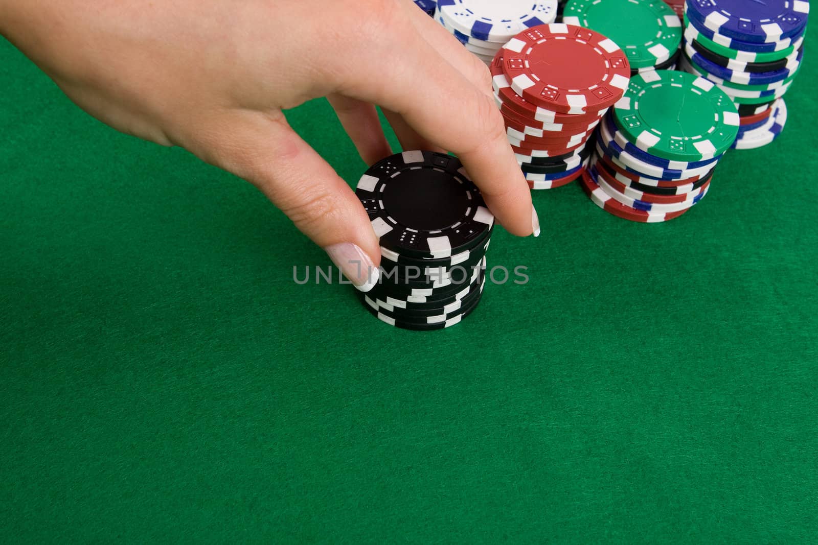 Female hand putting black poker chips into game.