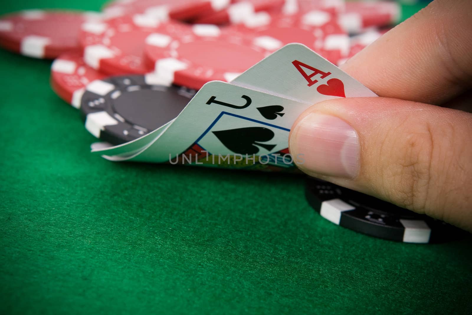 Ace of hearts and black jack with red poker chips in the background.