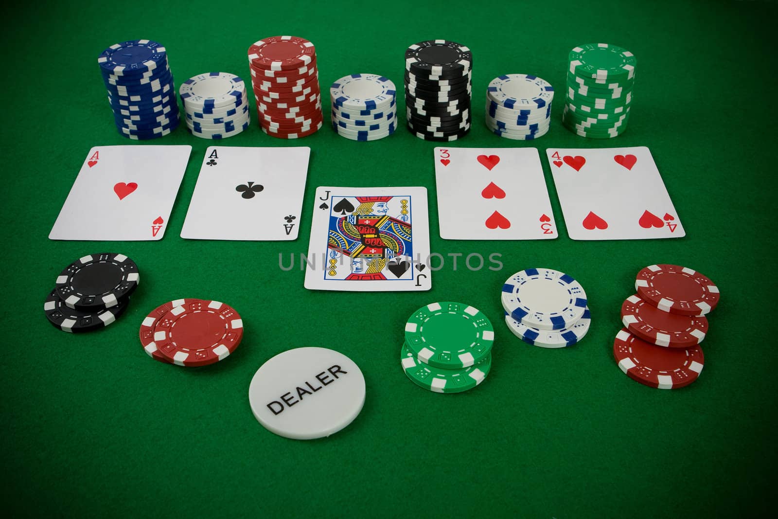 Poker set, cards and poker chips on green table.