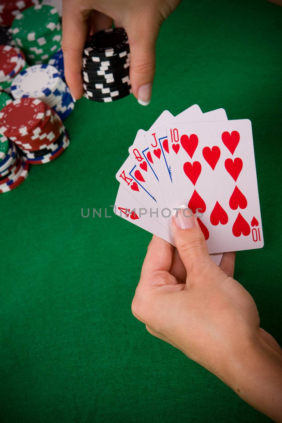 Cards with poker arrangement and female hand betting in the background.