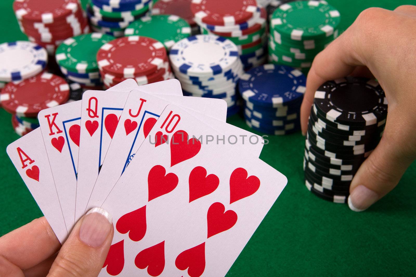 Cards with poker arrangement and female hand betting in the background.