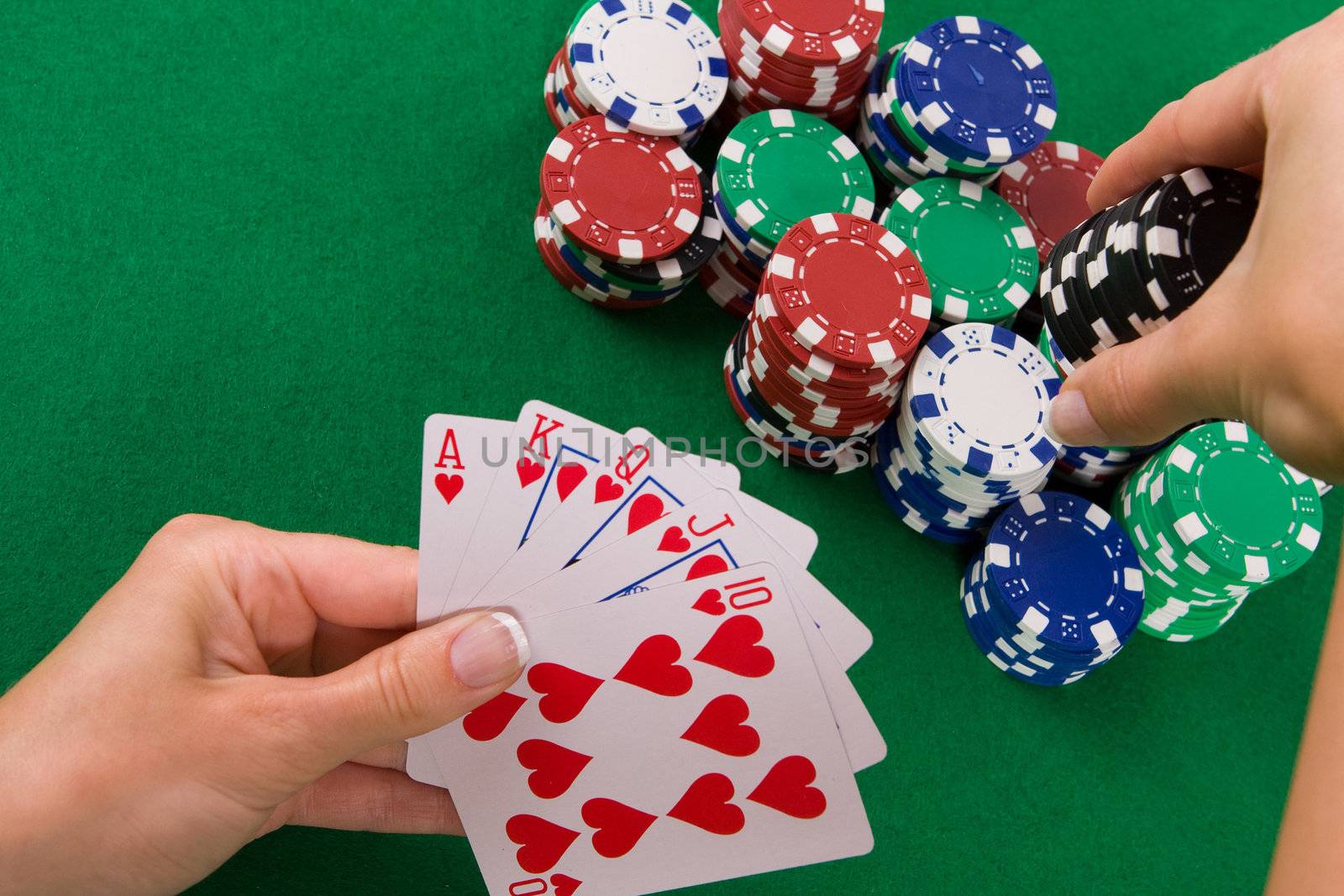 Cards with poker arrangement and female hand betting in the background.