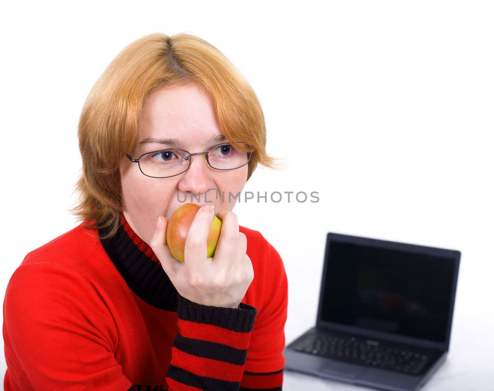 The woman in points bites an apple against the laptop