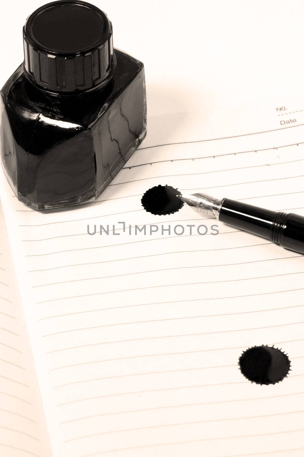 classic black fountain pen on open notebook with ink bottle with stain on page,sepia filter